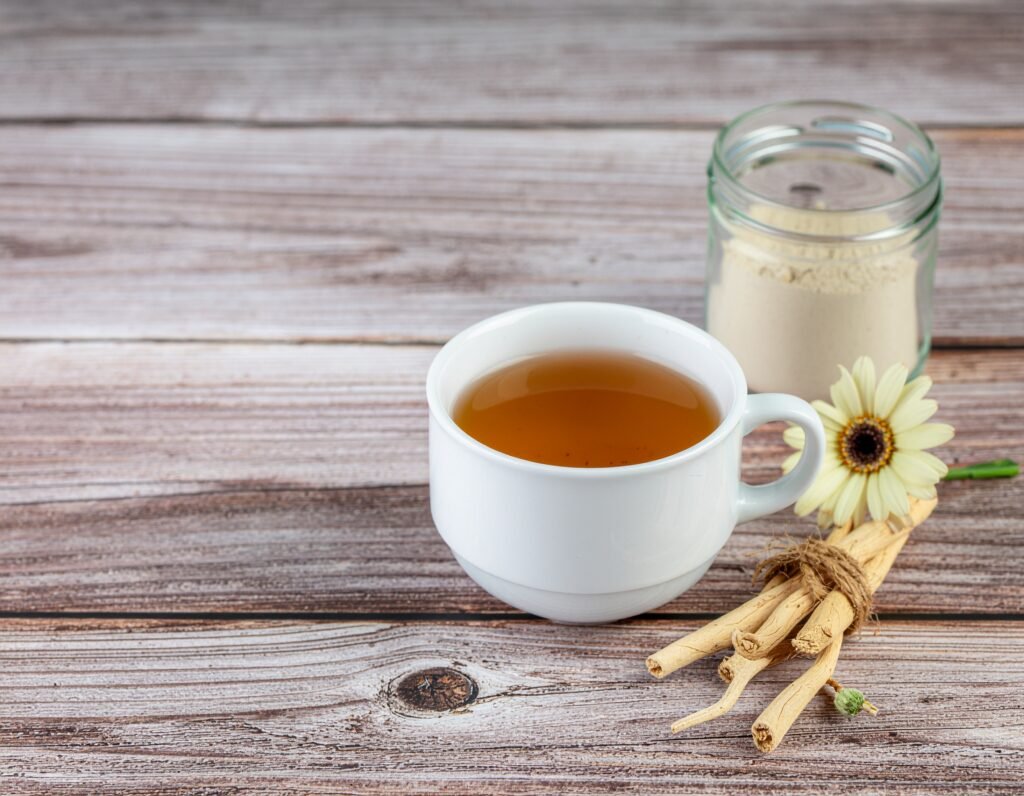 Cup of shatavari tea beside dried roots and powder