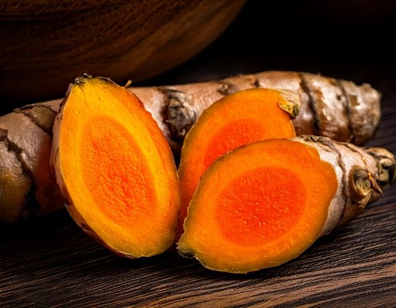 Macro shot of fresh turmeric rhizome, bright orange